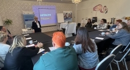 Grupa ludzi siedzi przy stole w sali konferencyjnej podczas spotkania