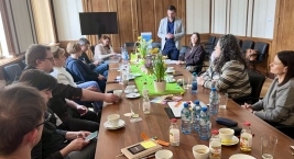 Zespół ludzi siedzący przy stole, zaangażowany w rozmowę i współpracę