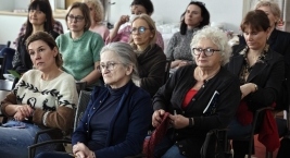 Wnętrze pokoju z grupą kobiet siedzących na krzesłach, zaangażowanych w rozmowę